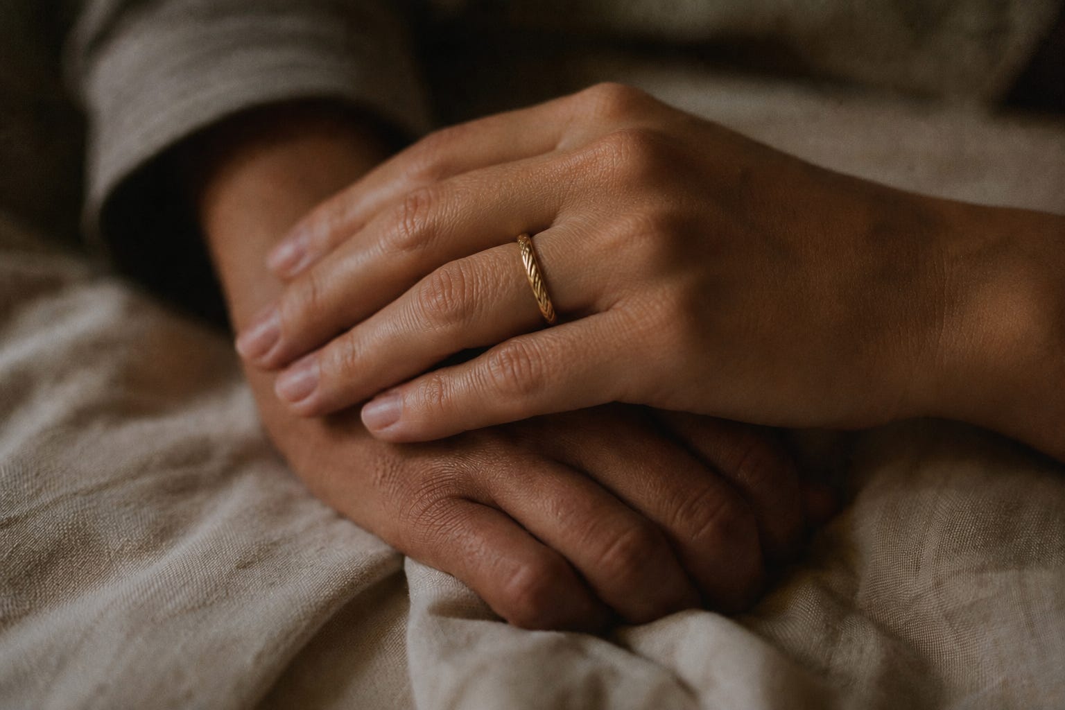 Two hands resting together on soft fabric